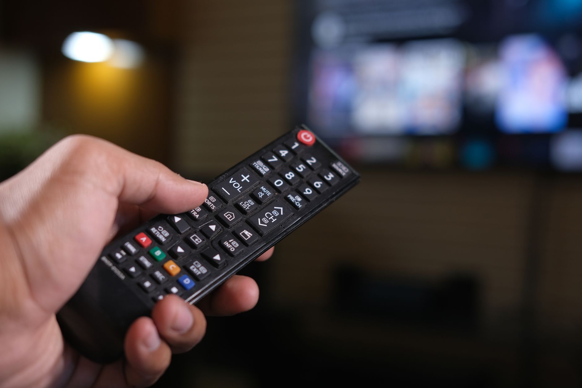 Fire TV Stick remote next to a television running the Downloader app